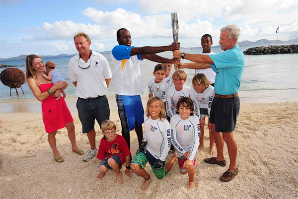 The arrival of the Queen's Baton in the Race Village brought much excitement to the BVI Spring Regatta as organisers secured a visit during its 288-day journey en route to the XX Commonwealth Games in Glasgow, Scotland. Nanny Cay General Manager, Miles Sutherland-Pilch and family (left), local youth sailors and Regatta Chairman, Bob Phillips (right) proudly display the baton. (Photo: Todd vanSickle)